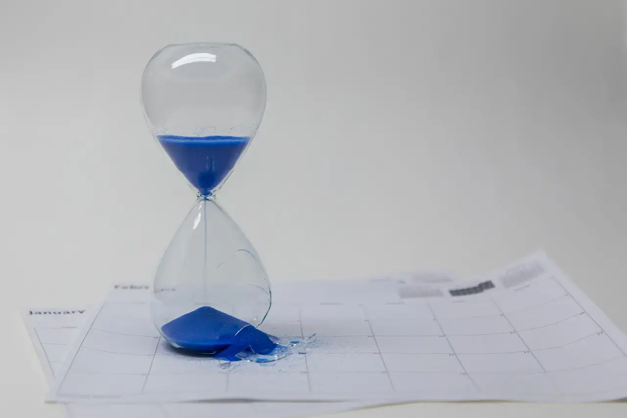 an image of an hour glass on top of a paper calendar